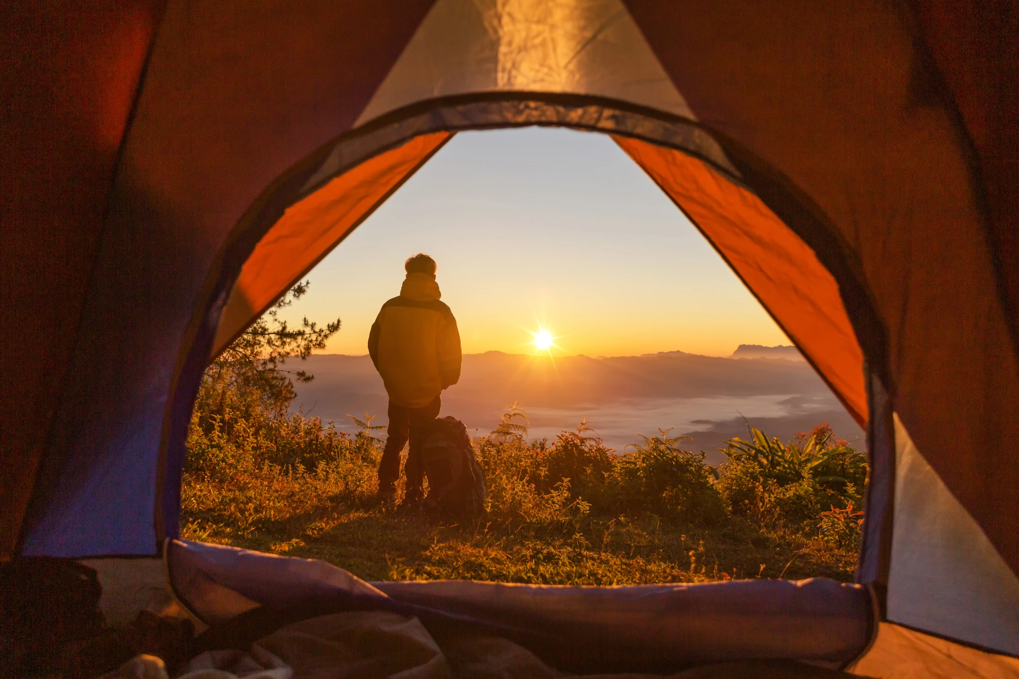 hiker stand camping near orange tent backpack mountains